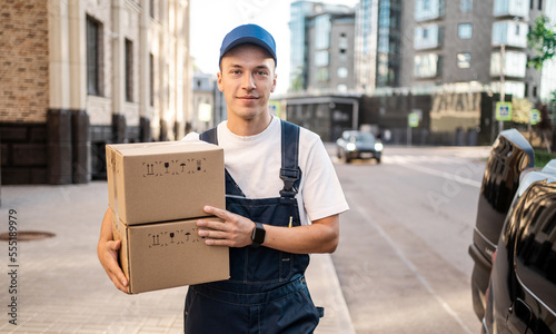 A male courier works in a home delivery service, dressed in a uniform. Fast delivery in food boxes.