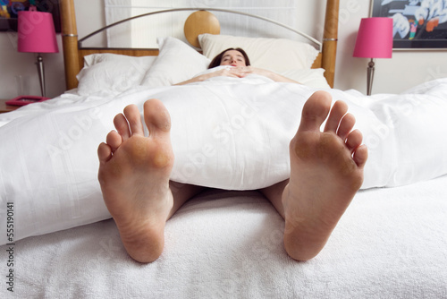 Young woman sleeping in a bedroom with feet showing.