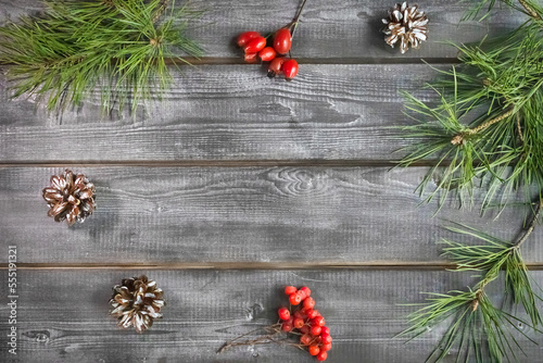 Christmas card. Fir branches, red berries and cones on a wooden background. Place for text photo