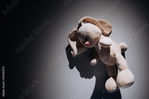 Teddy rabbit is alone in a dark room. Child abuse, solitude and violence concept