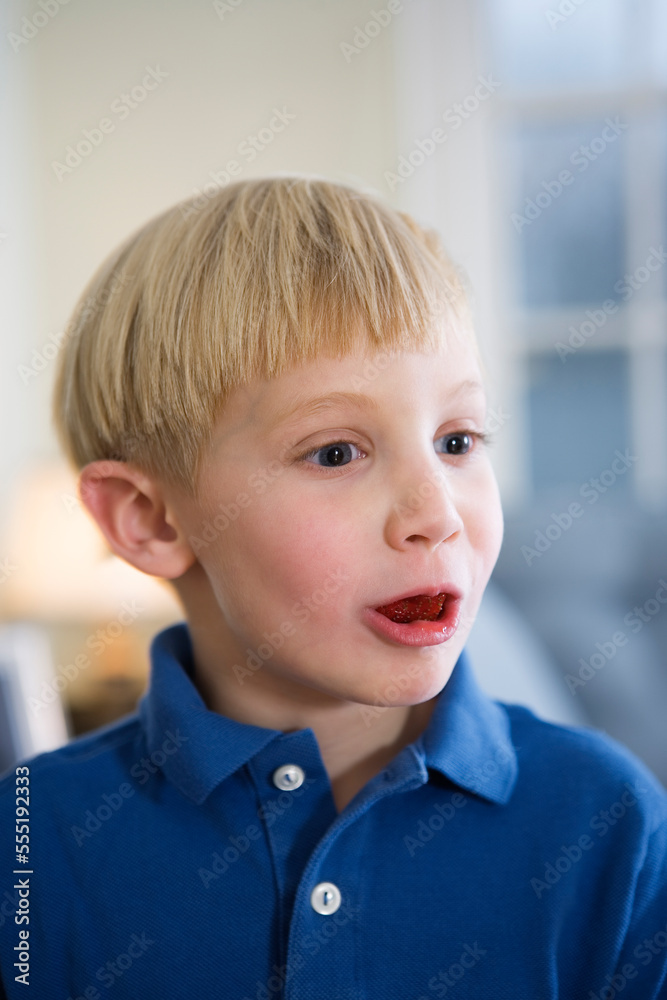 Close up of a boy eating a strawberry.