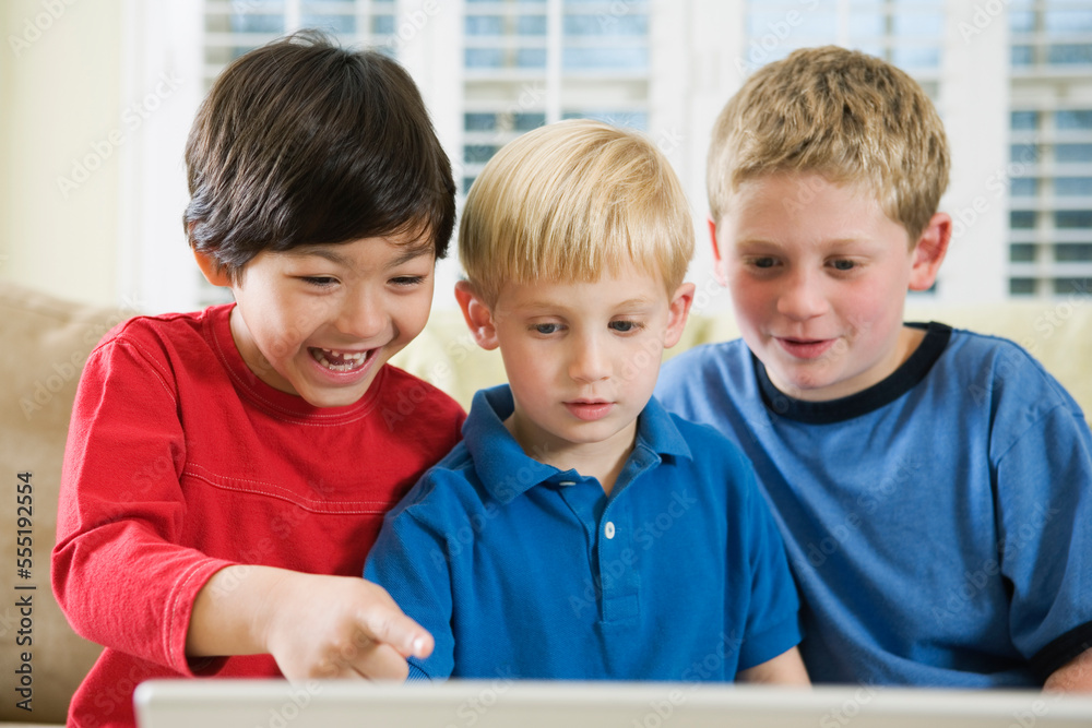 View of three friends looking at a laptop. View of three friends looking at a laptop.