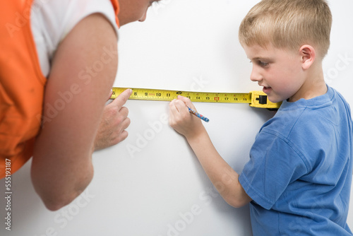 View of a woman and boy using tape measure.