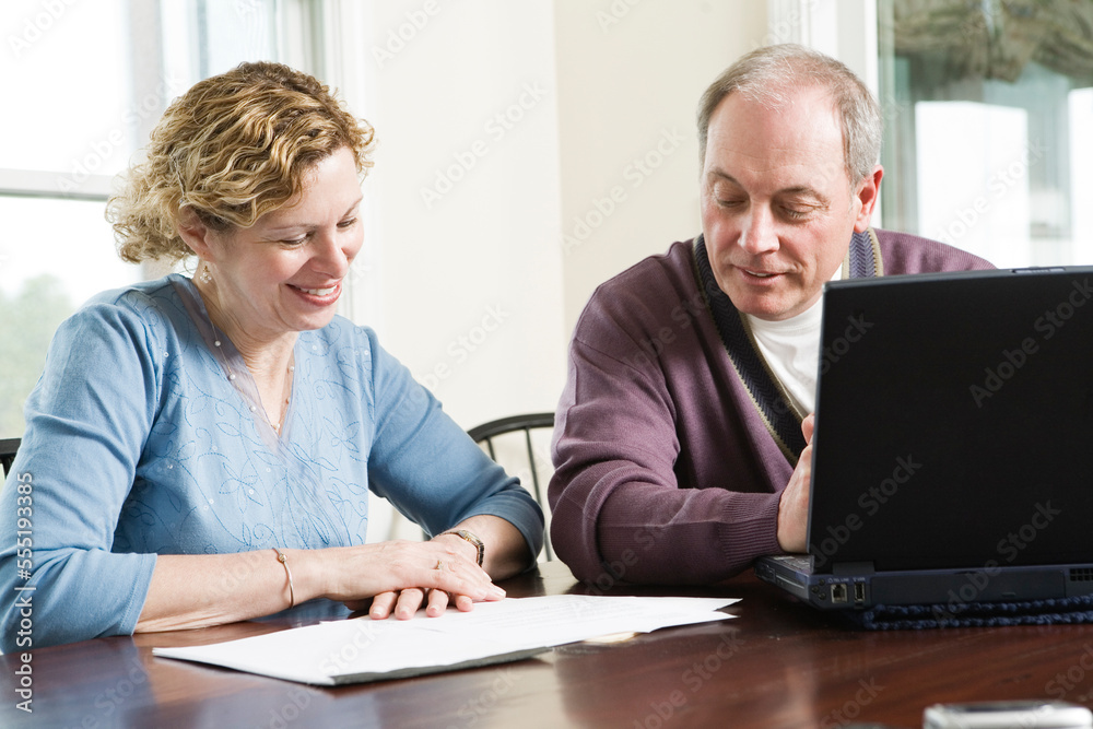 View of a mature couple discussing by table. View of a mature couple discussing by table.