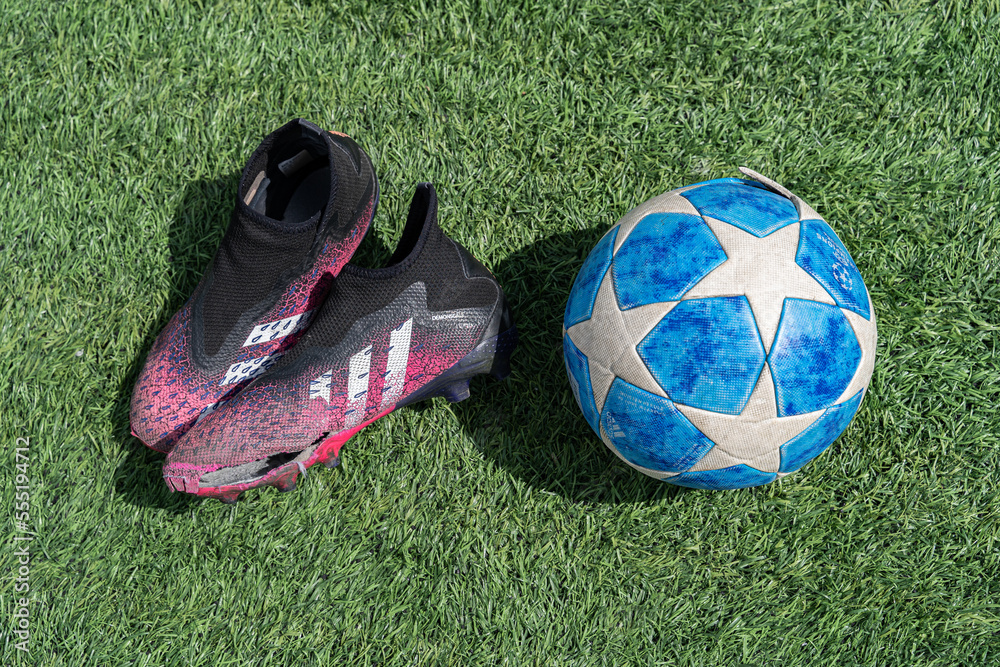 A torn football boot with a torn soccer ball on the green artificial
