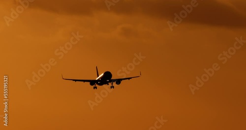 Sunset in orange tones and colors and dark silhouette of commercial passenger plane in flight. Provision of transport services by airline for tourists and travelers. Air transportation of passengers