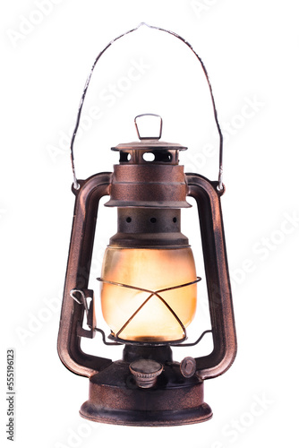 Gas lantern with burning light, isolated on a white background. An antique vintage lamp. Hipster accessory. Camping light. Interior decoration. Rusty, covered with patina. Wire handle