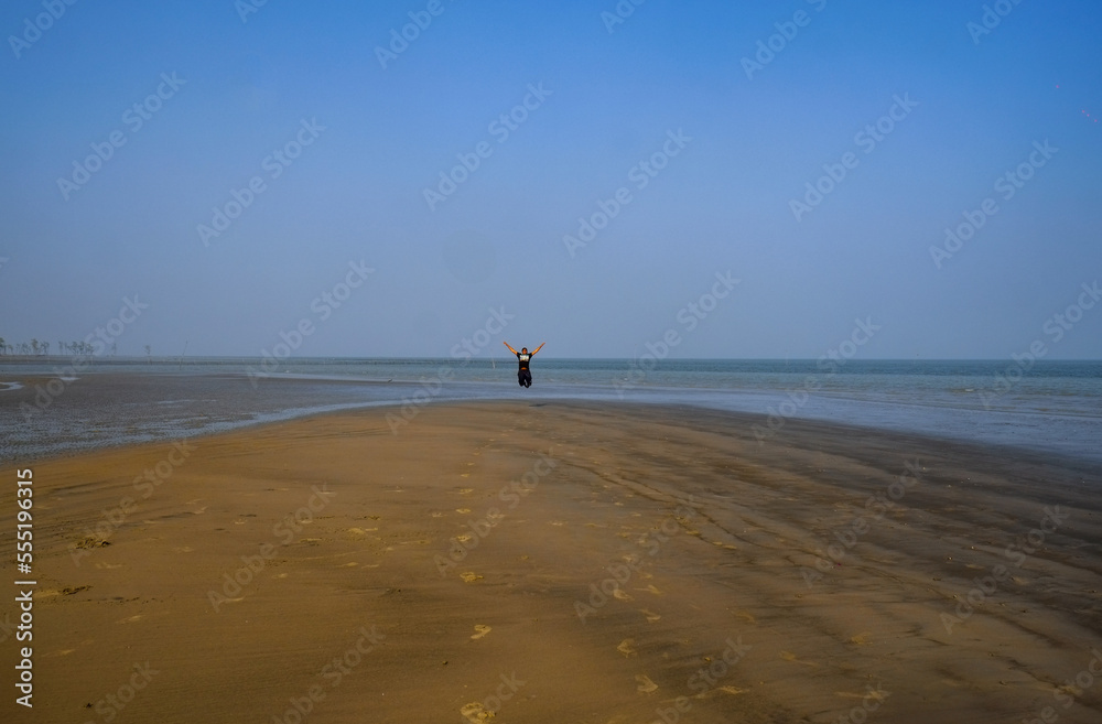 Young boy jumping with joy in a sea beach 