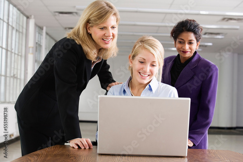 Three business colleagues looking at a laptop.