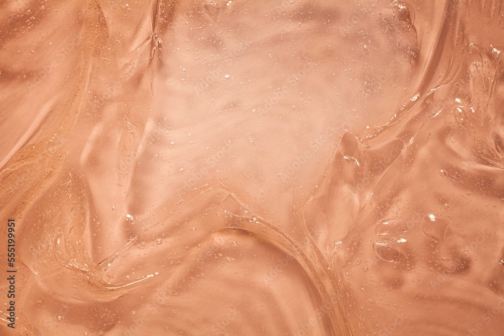 Fototapeta premium Liquid orange cosmetic smudge cream gel background 
