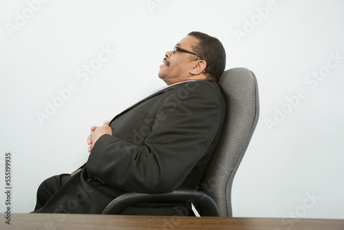 Side profile of a businessman sitting in an office chair and thinking photo