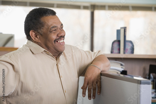 Businessman leaning on a cubicle in an office photo