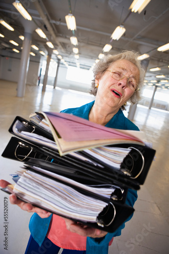 View of a senior woman carrying heavy files. photo