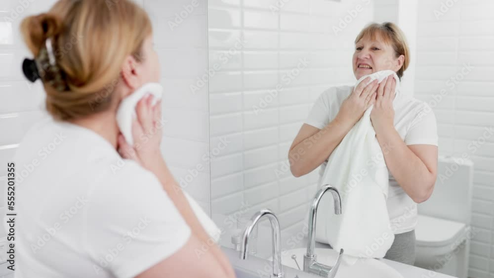 Young woman wiping her face with towel in bathroom Young woman wiping her face with towel in bathroom