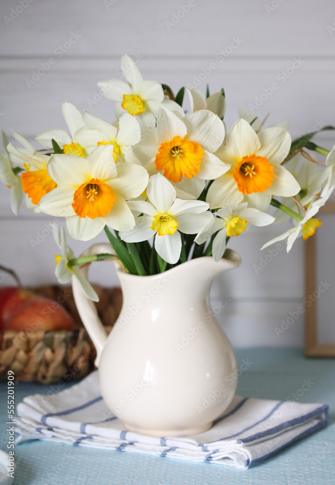 daffodils in a jug on the table in the cottage interior.