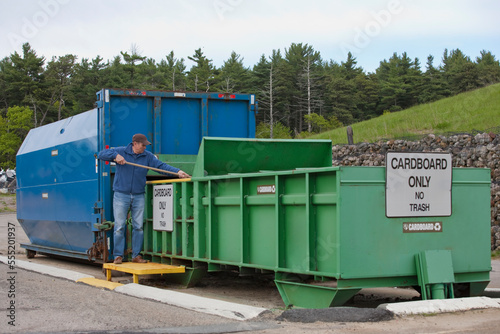 Engineer arranging cardboard at Cardboard Only recycling compactor connected to container photo