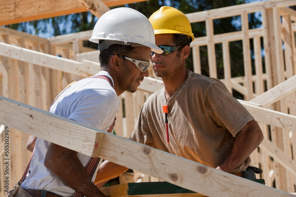 Carpenters lifting a laminated beam at a construction site