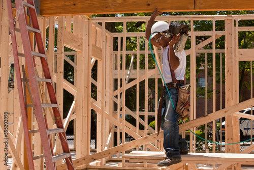 Carpenter standing at a construction site holding a nail gun