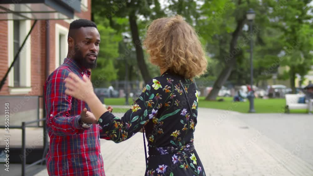 Young woman smile at strange man walking with boyfriend outdoors. 