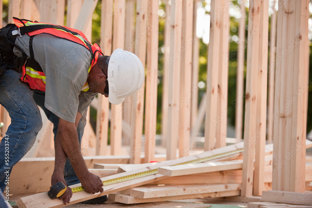 Carpenter measuring wood for framing Carpenter measuring wood for framing