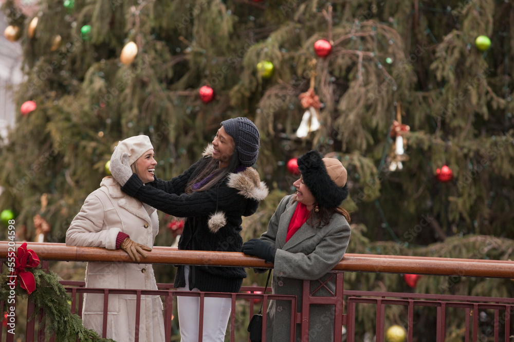 Three women standing on a balcony having fun, with Christmas decorations behind them; Boston, Massachusetts, United States of America Three women standing on a balcony having fun, with Christmas decorations behind them; Boston, Massachusetts, United States of America