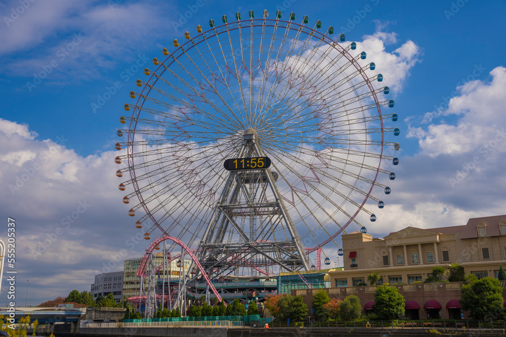 This image features a large ferris wheel in Japan with a cloudy blue sky in the background.