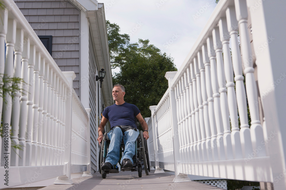 Man with spinal cord injury in a wheelchair on the top of home access ramp Man with spinal cord injury in a wheelchair on the top of home access ramp