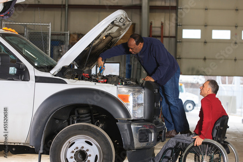 Technician performing engine maintenance with supervisor in wheelchair with spinal cord injury photo