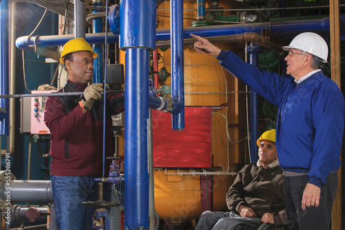Power plant engineers one with spinal cord injury inspecting demineralization pipes photo