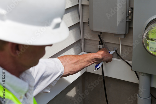 Cable installer applying weather proof sealant to the cable installation photo