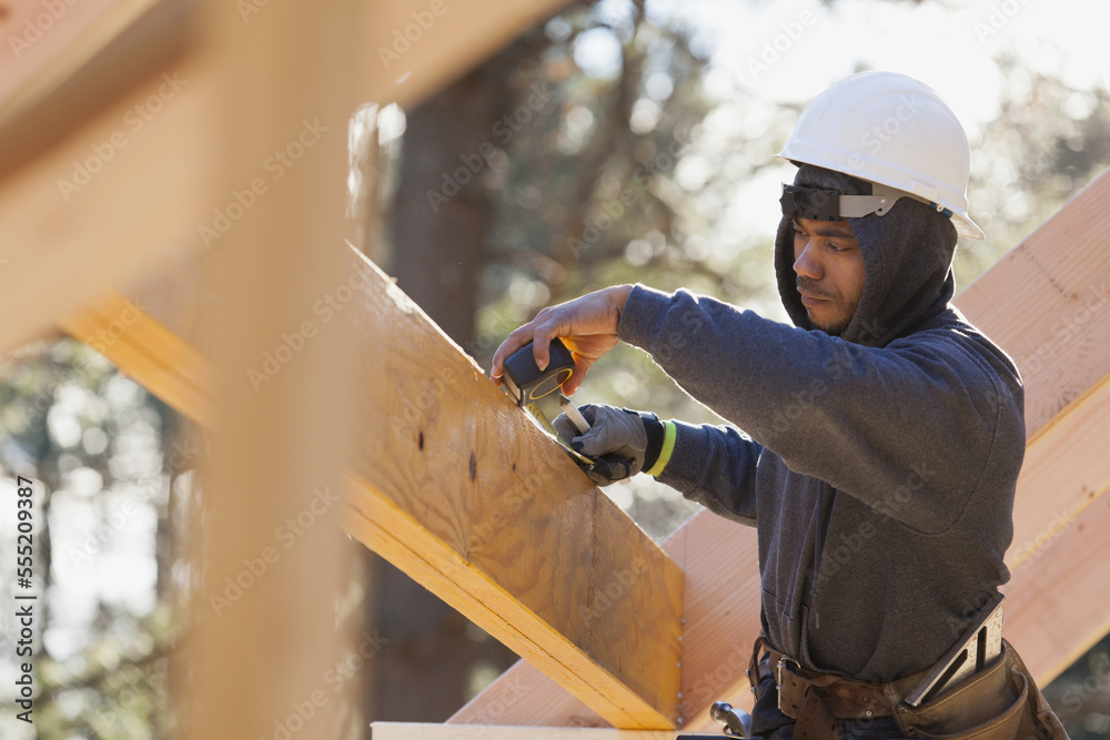 Carpenter measuring a laminated beam