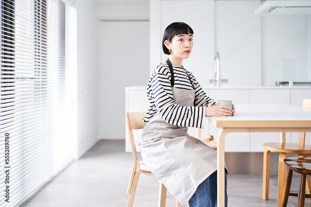 エプロン姿で休憩する若い女性 エプロン姿で休憩する若い女性