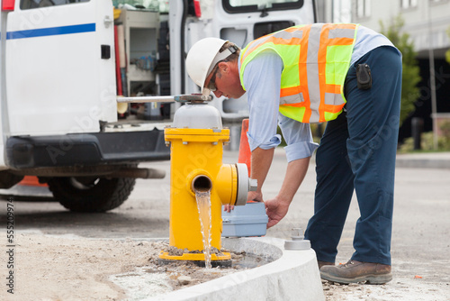 Department of public works engineer draining a hydrant and preparing to take a water sample