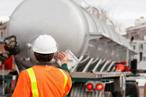 Environmental engineer directing tanker truck for hazardous waste cleanup