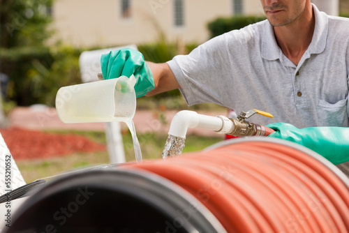 Pest control technician mixing chemicals with water into chemical tank photo