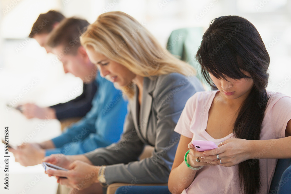 Passengers seated in an airport lounge all using electronics Passengers seated in an airport lounge all using electronics