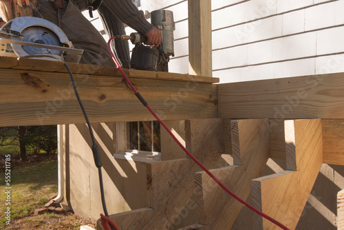 Hispanic carpenter nailing decking at stair stringers photo