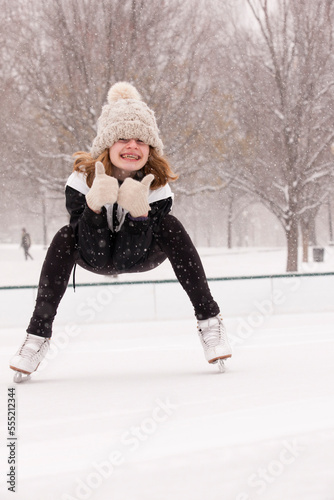 Girl with thumbs up ice skating on rink