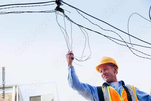 Cable lineman on ladder fixing dangling wires
