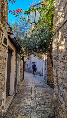 Tourist man walking in typical Mediterranean Street in the historic old city center (star grad) Budva, Montenegro, Adriatic Sea, Montenegro, Balkan, Europe. Warm idyllic atmosphere stone houses