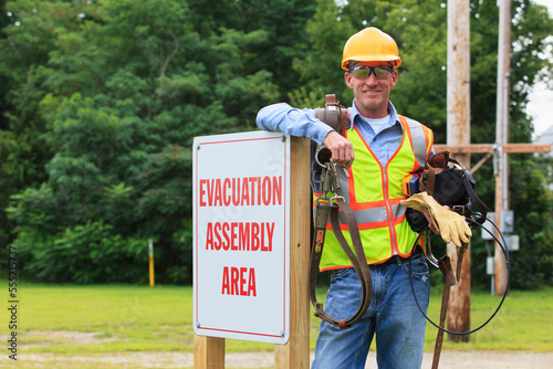 Communications engineer with climbing equipment and tool belts at evacuation assembly area photo