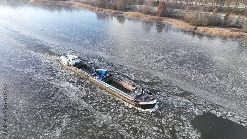 Freight ship barge ploughing through ice on a froze Drontermeer lake during a cold winter day in The Netherlands photo