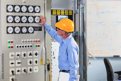 Electrical engineer inspecting power plant controls in central operations room of power plant