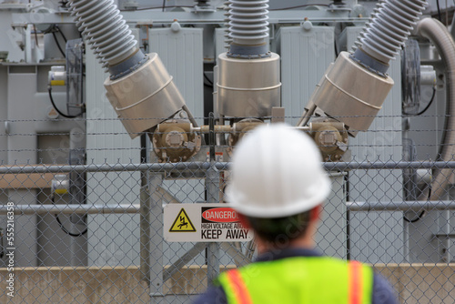 Power engineer looking at high voltage transformer at a power plant photo
