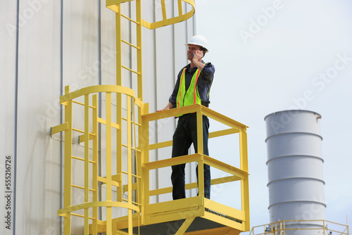 Industrial engineer on safety cage of fuel storage tank at power plant photo