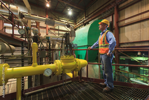Engineer in electric power plant inspecting condenser room piping photo