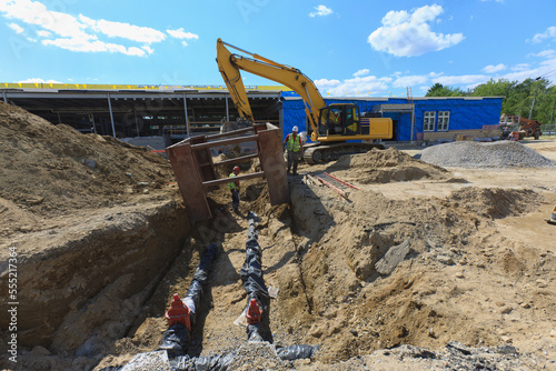 Excavator and trench shield for construction workers at water pipe laying site photo