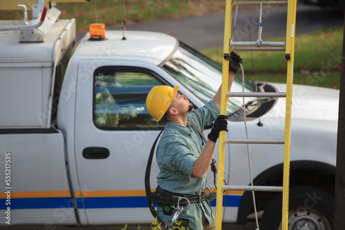 Lineman placing ladder at power pole
