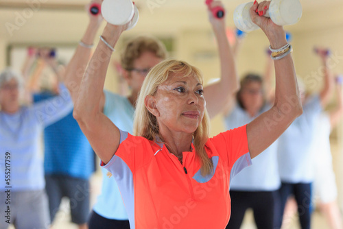 Female instructor lifting free weights in a senior's fitness class photo