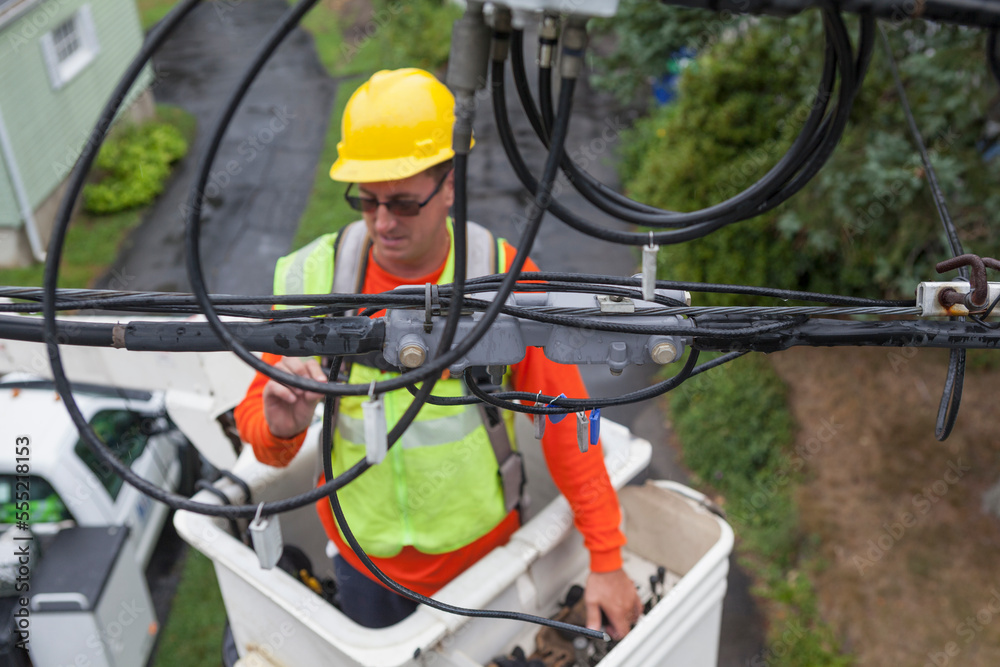Cable lineman examining connections from bucket lift Cable lineman examining connections from bucket lift